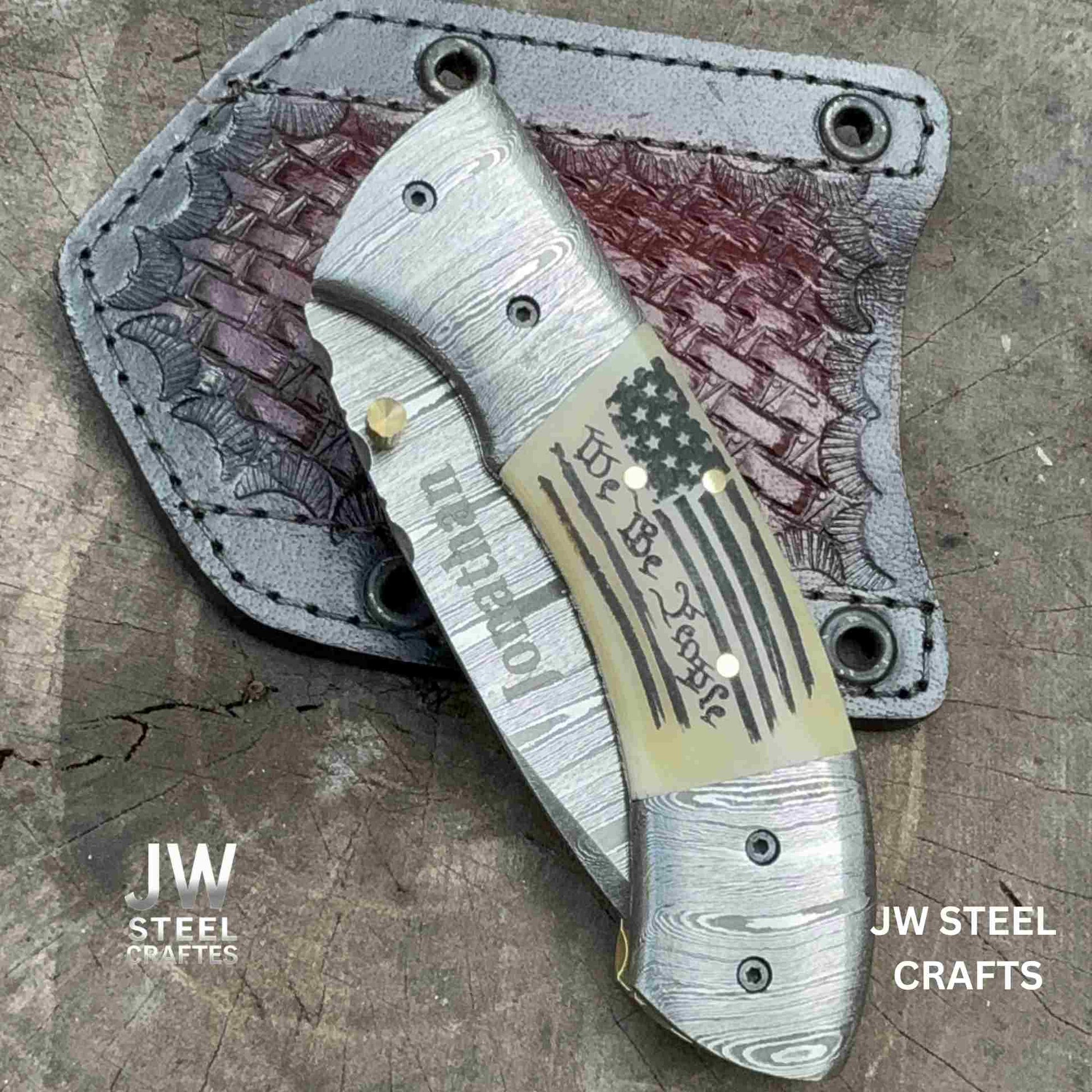 Folding knife with decorative blade and leather sheath on a textured surface, branded 'JW Steel Crafts'.