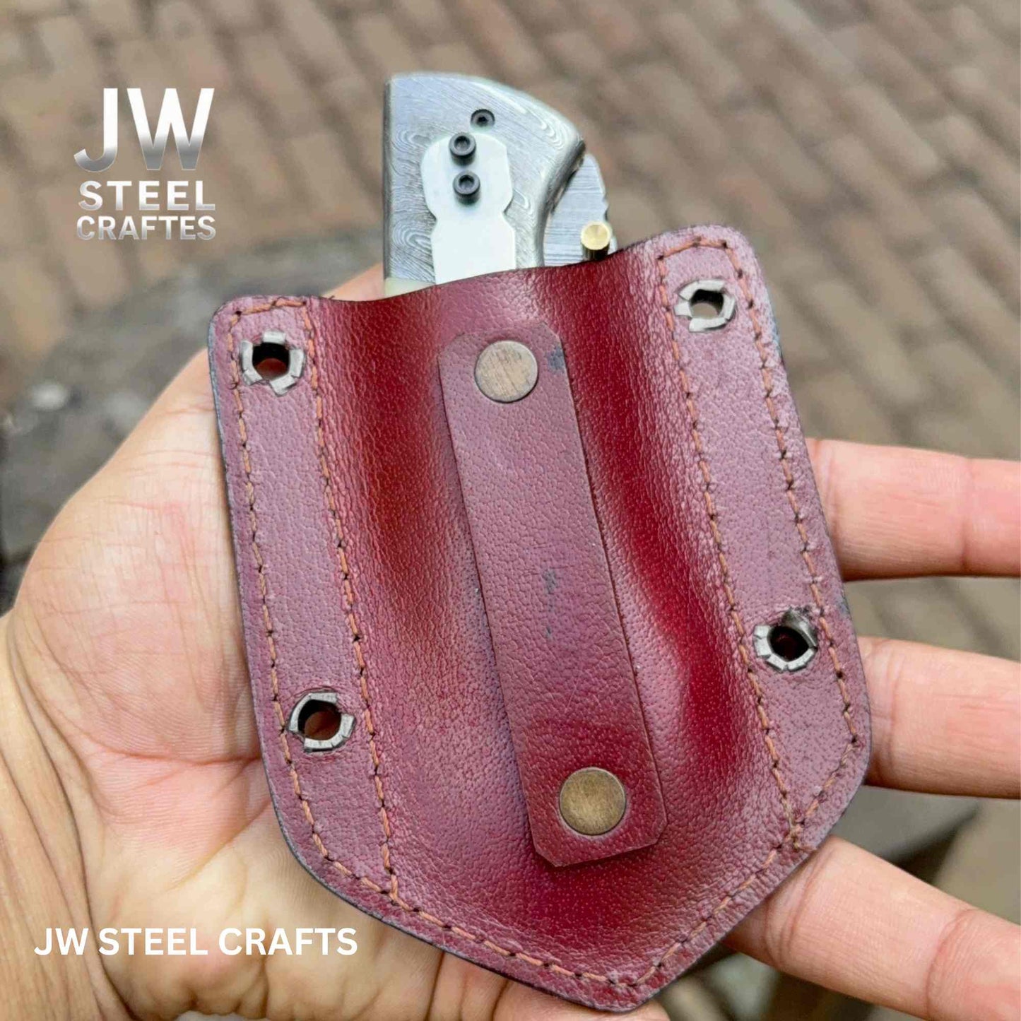Red leather knife sheath held by a hand with 'JW Steel Crafts' branding.