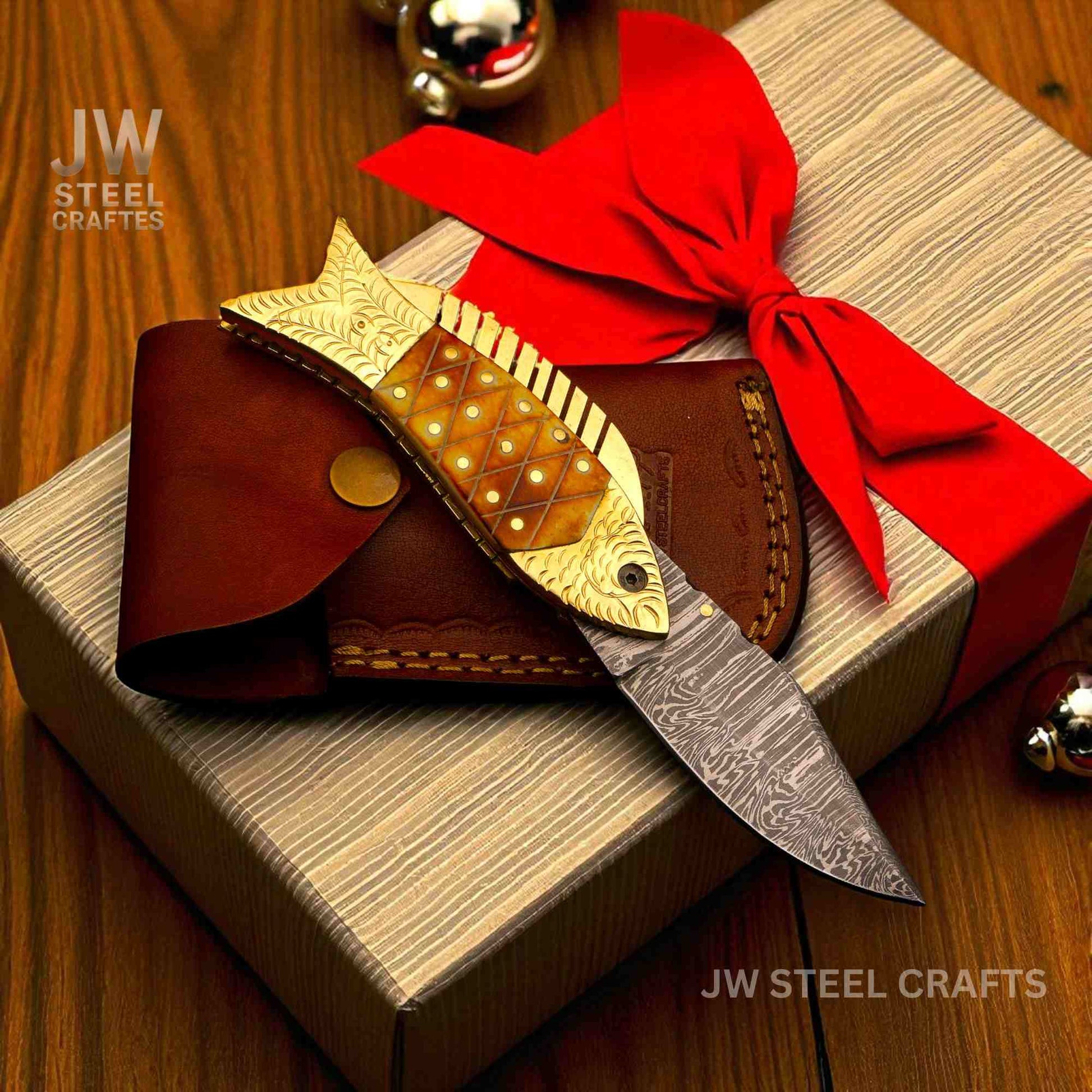 Decorative knife with gold embellishments and a red bow on a gift box, branded 'JW Steel Crafts'.