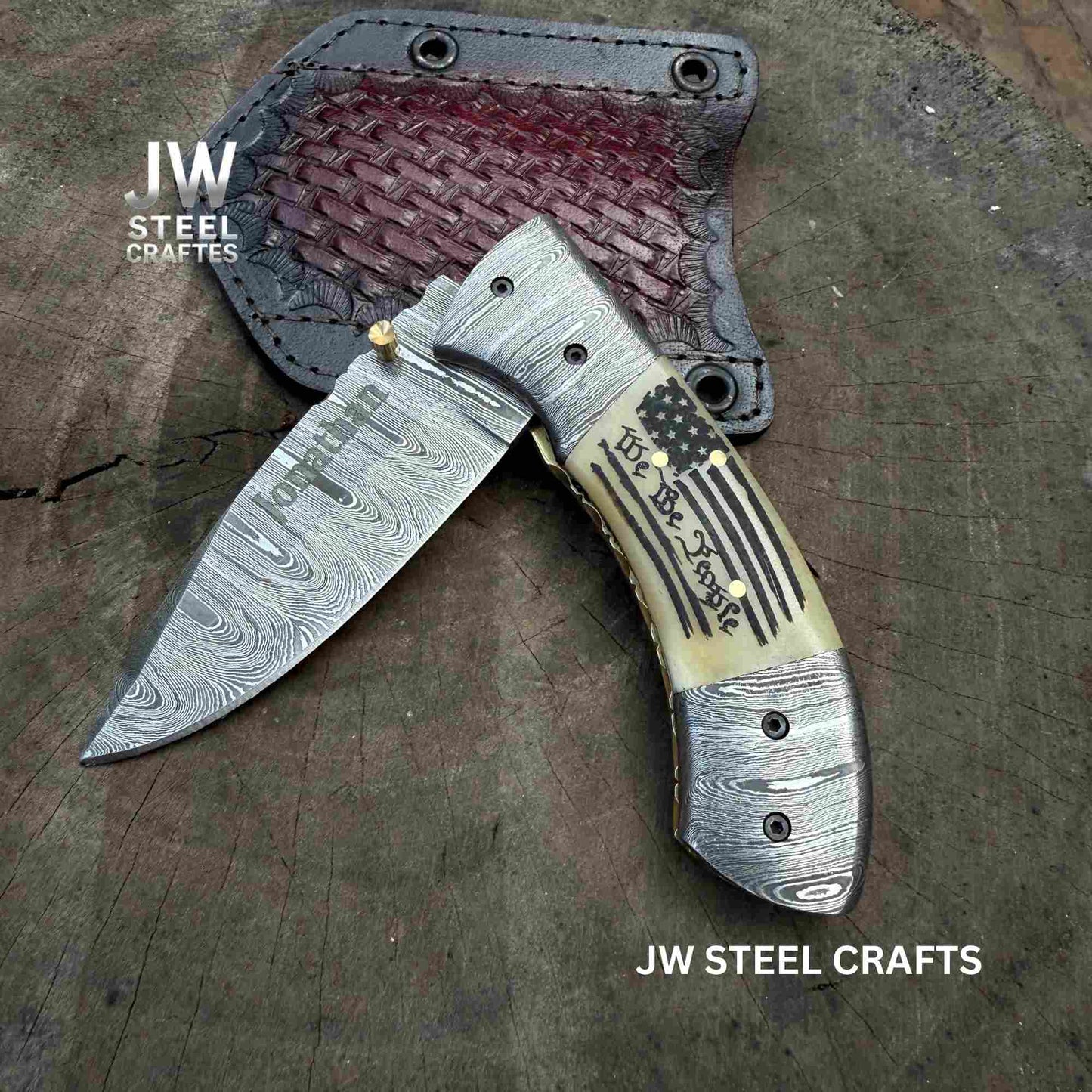 Folding knife with decorative handle on a wooden surface, branded 'JW Steel Crafts'.