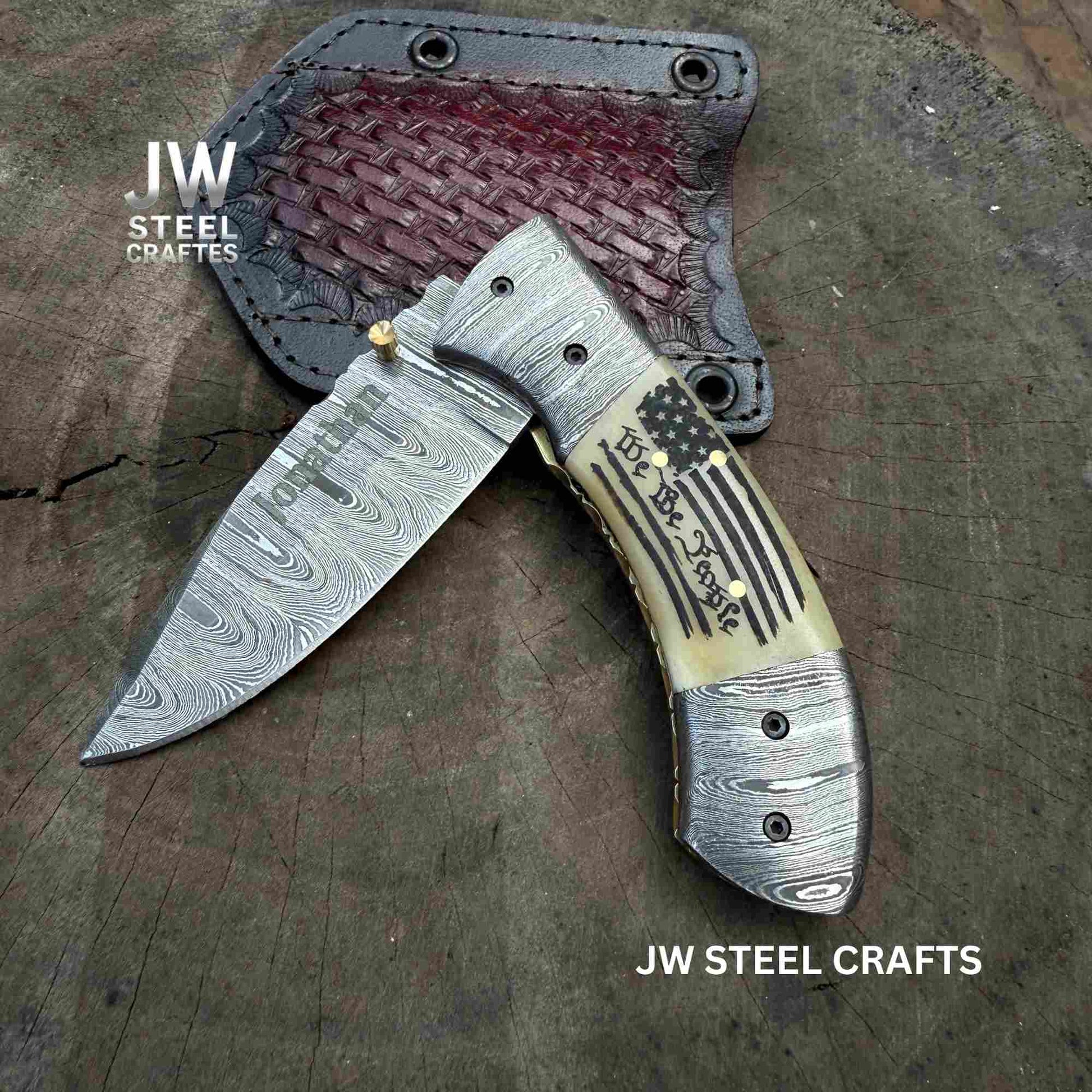 Folding knife with decorative handle on a wooden surface, branded 'JW Steel Crafts'.