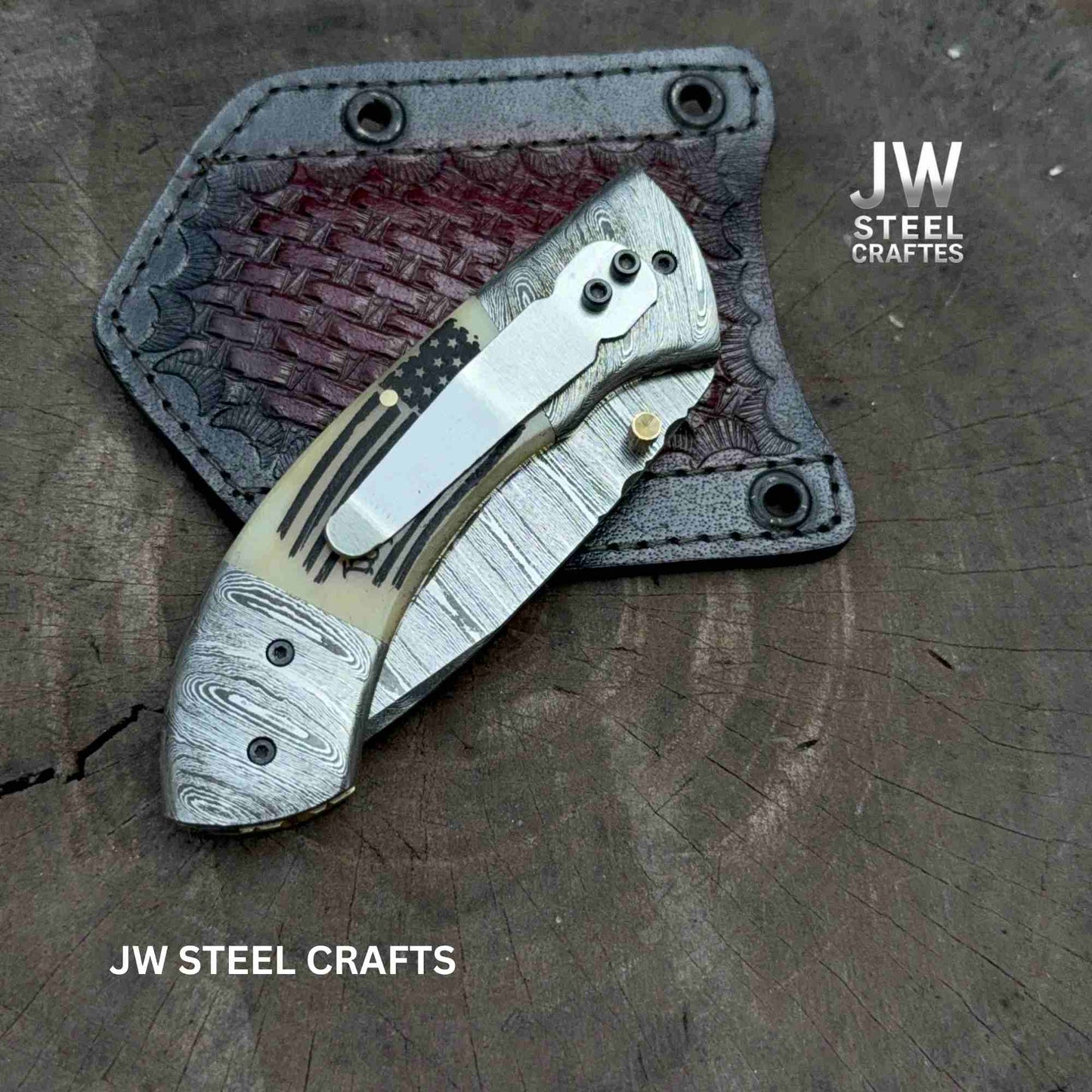 Folding knife with leather sheath on a wooden surface, branded 'JW Steel Crafts'.