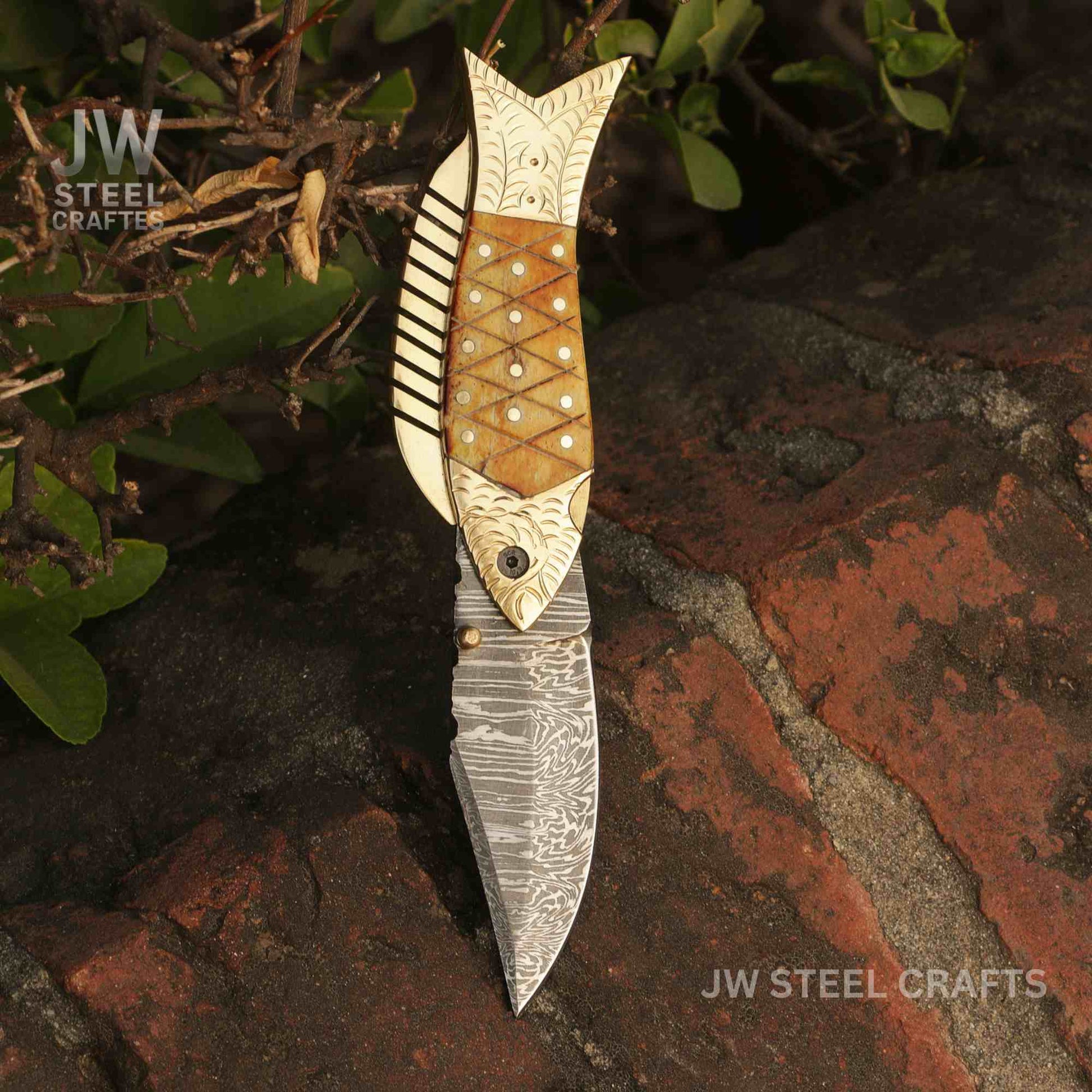 Decorative knife with artistic handle on a textured surface, featuring 'JW Steel Crafts' branding.