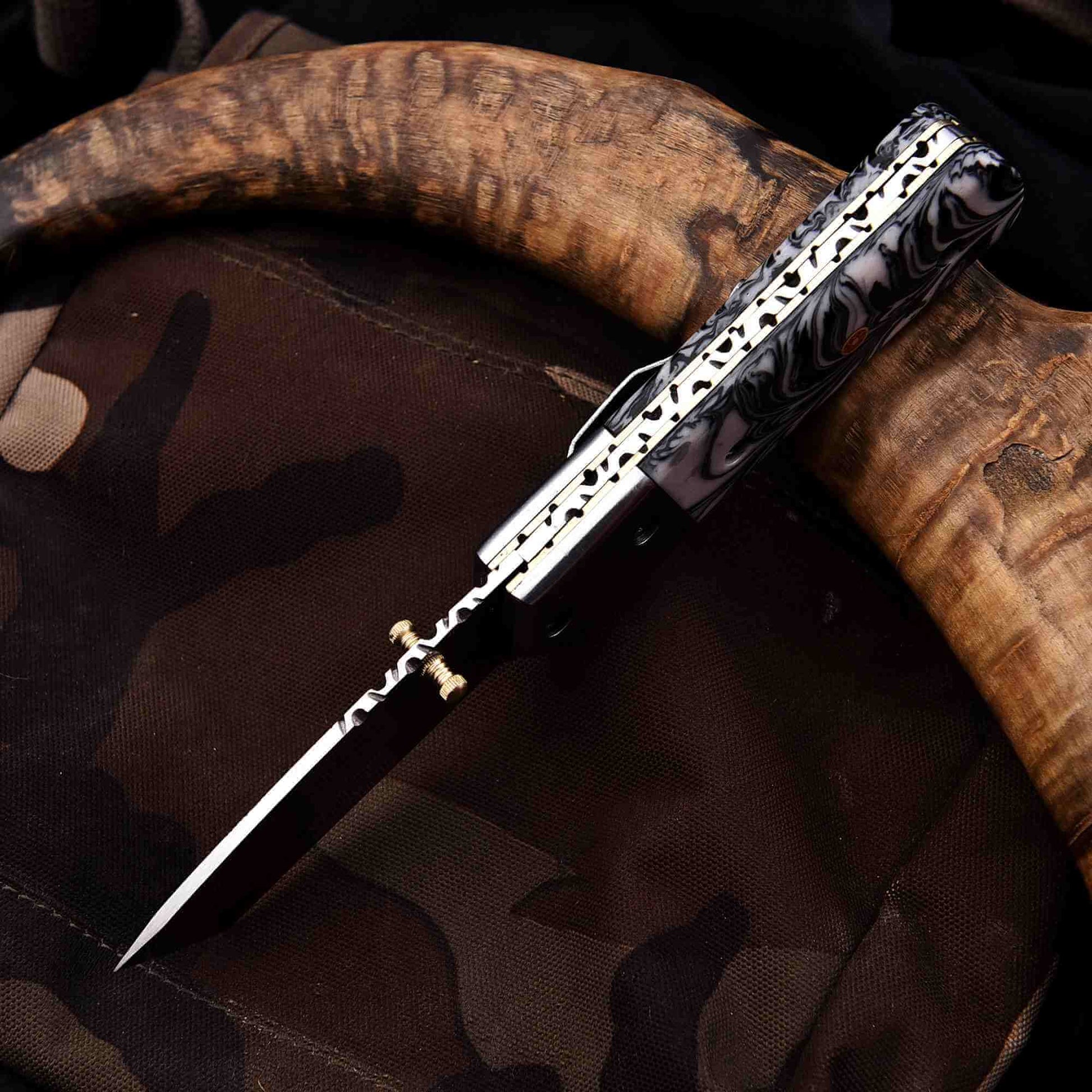 Stainless steel folding knife spine view showing liner lock mechanism and filework, with marble resin handle