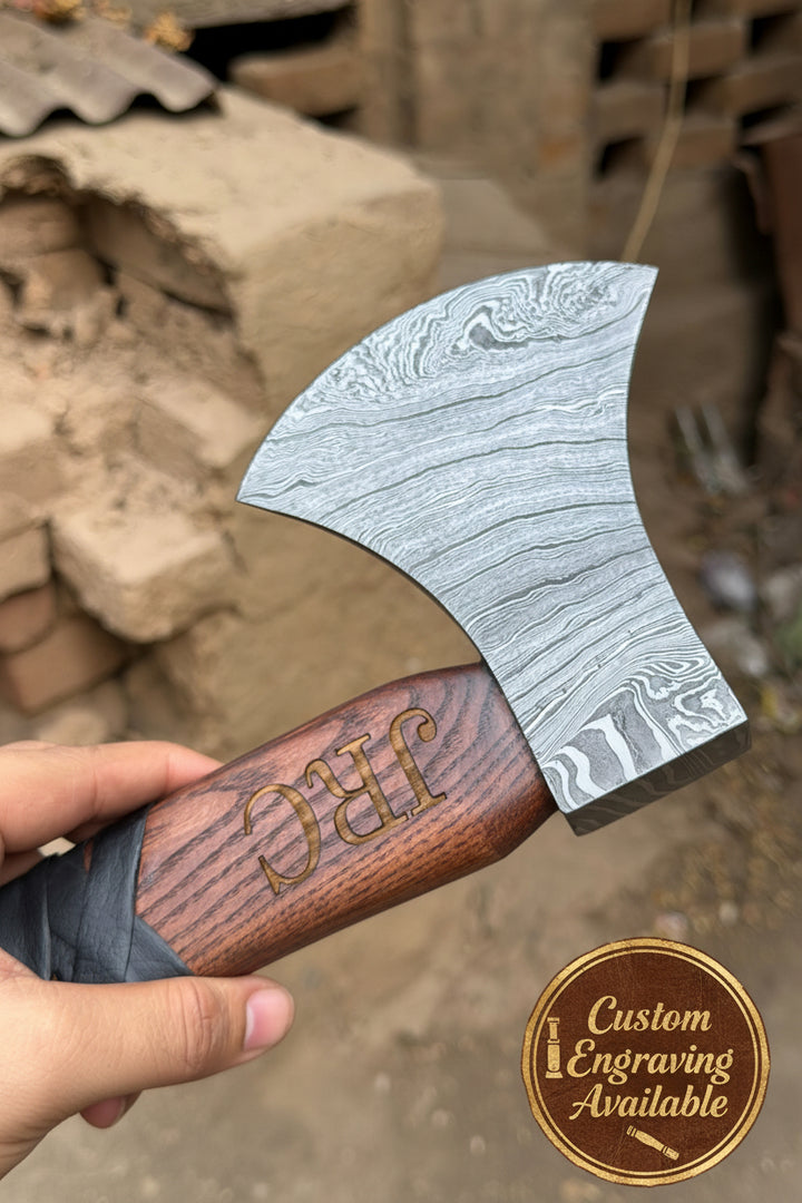 Handheld axe with a wooden handle and decorative blade, set against a natural background.