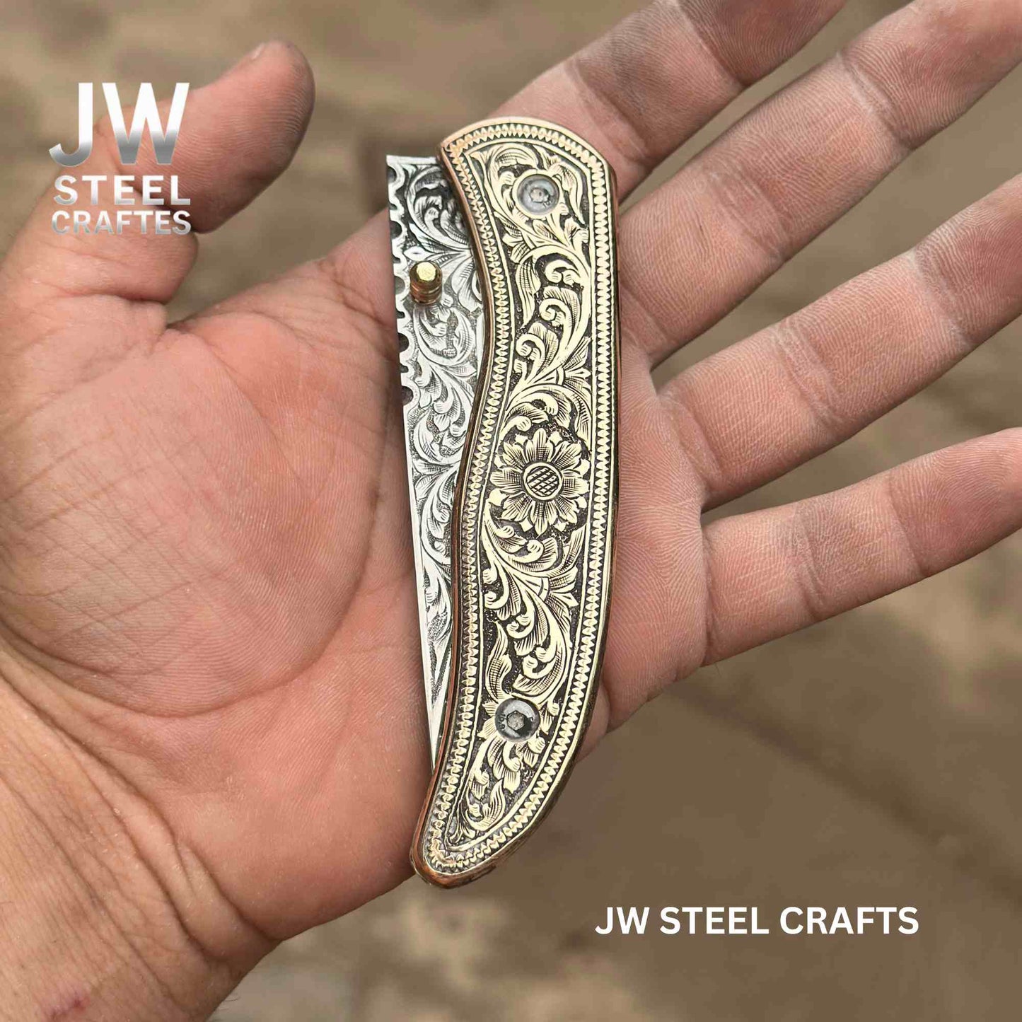 Decorative knife handle held in a hand with 'JW Steel Crafts' branding.