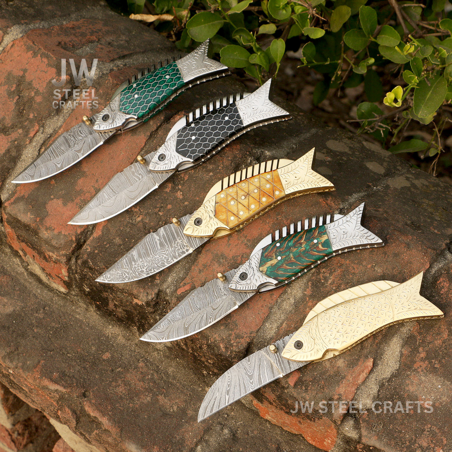 Five decorative knives with unique patterns on a stone surface, branded 'JW Steel Crafts'.