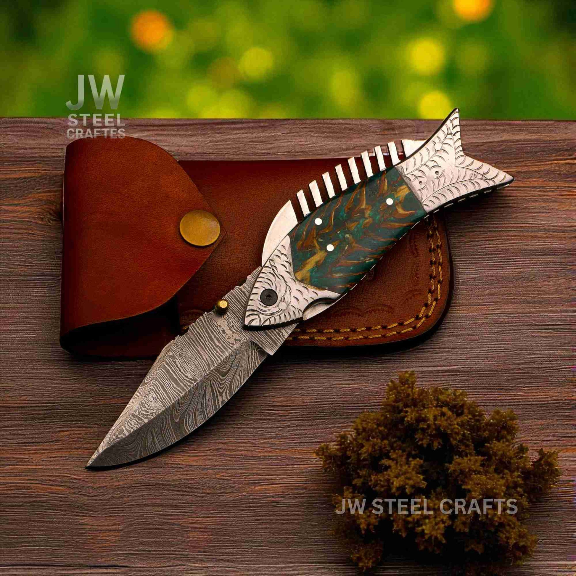 Decorative knife with wooden handle and leather sheath on a wooden surface, branded 'JW Steel Crafts'.