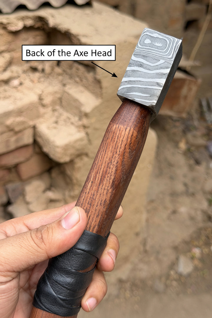 Hand holding a hammer with a wooden handle and metal head against a blurred background