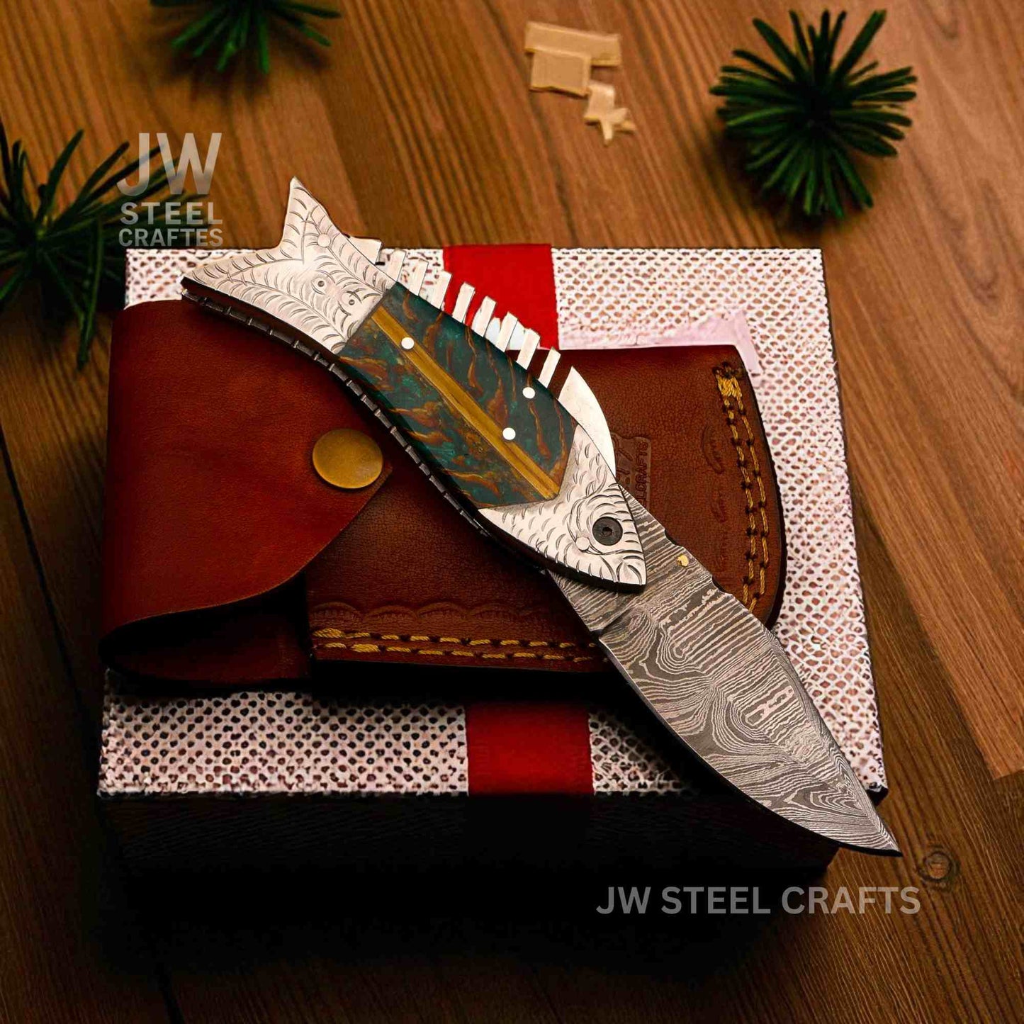 Decorative knife with artistic blade design on a wooden surface, branded 'JW Steel Crafts'.