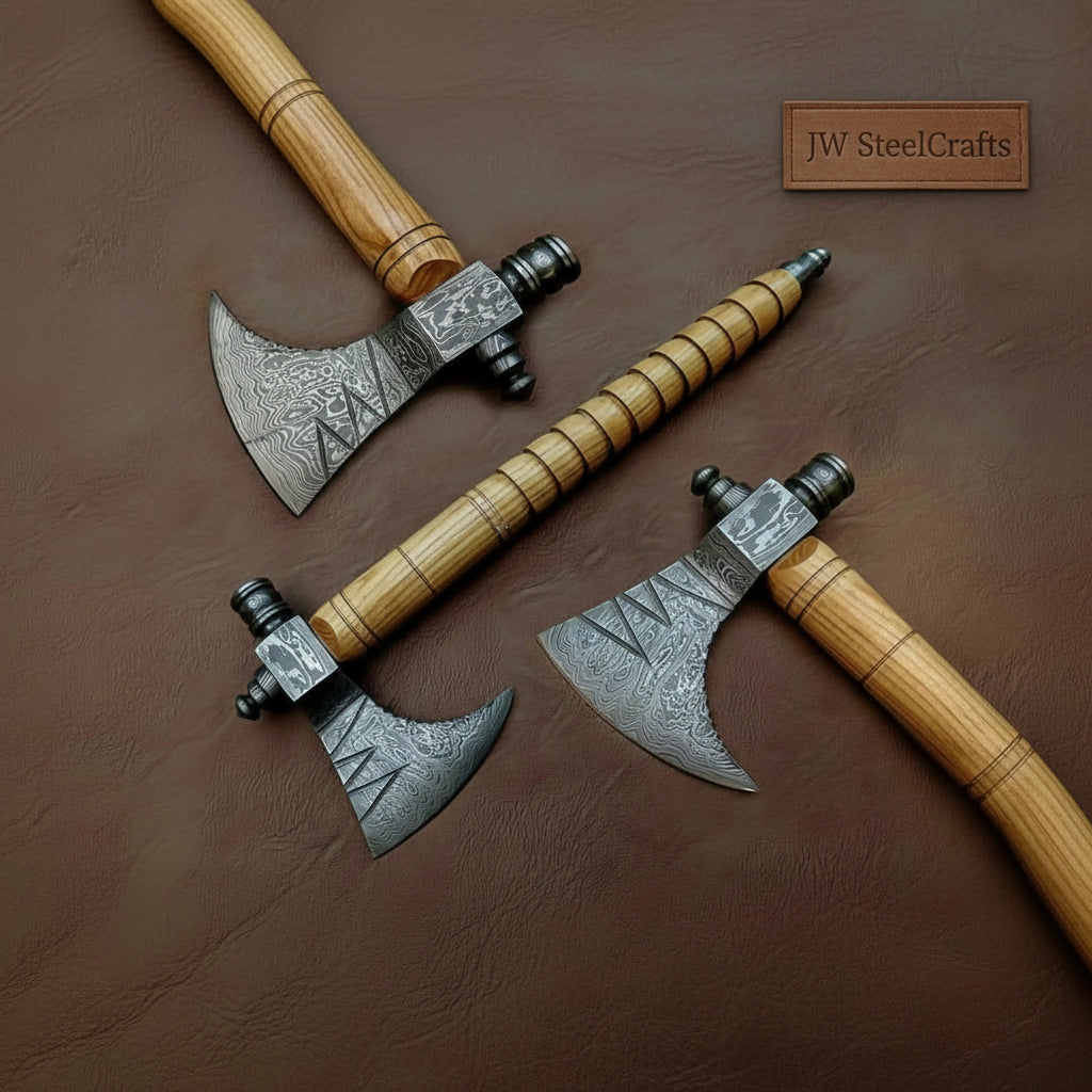     Crimsonedge Damascus bearded axes arranged on a dark leather surface with turned wooden handles and engraved steel heads.