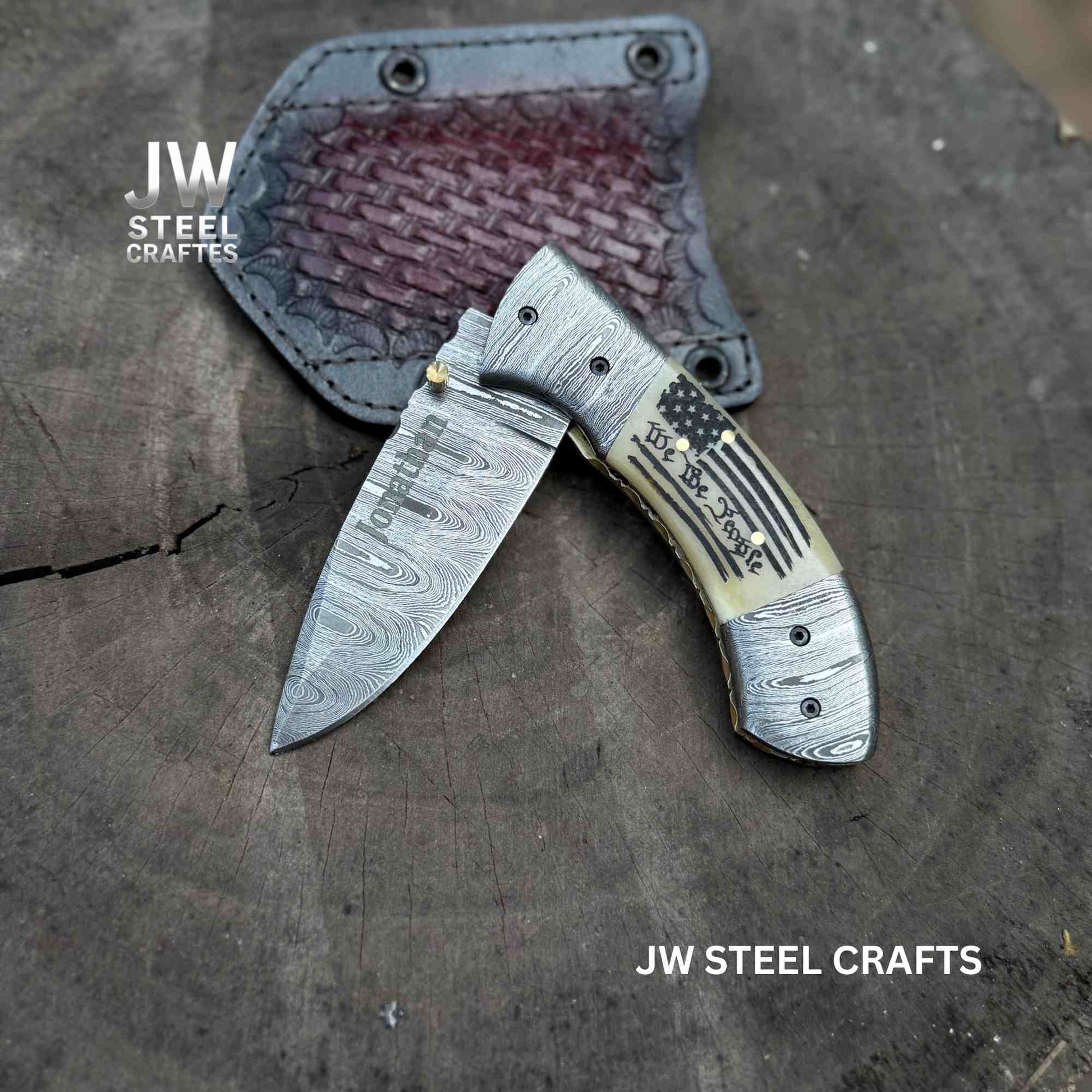 Folded knife with decorative handle on a wooden surface, branded 'JW Steel Crafts'.