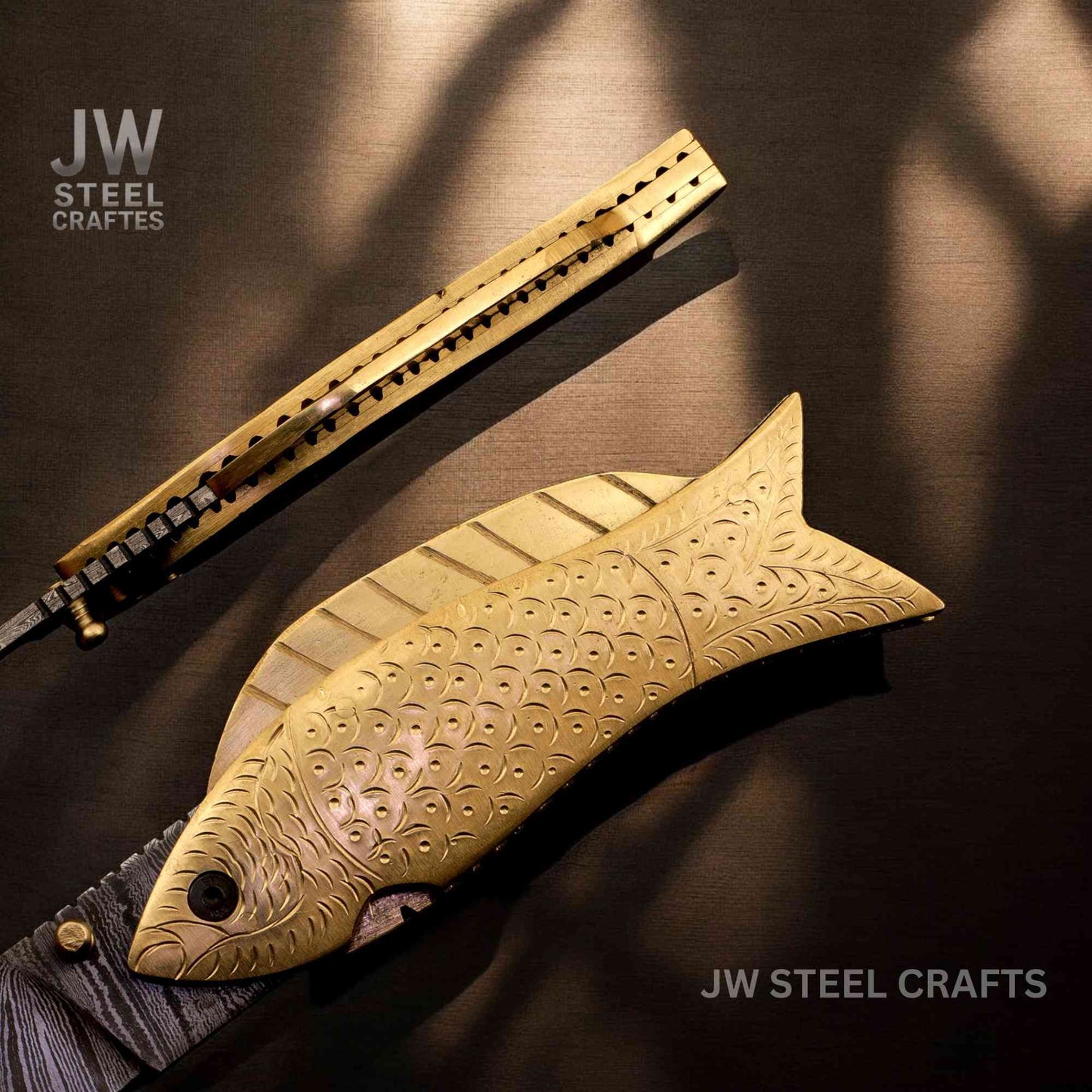 Decorative fish-shaped tool with engraved details on a dark background, branded 'JW Steel Crafts'.
