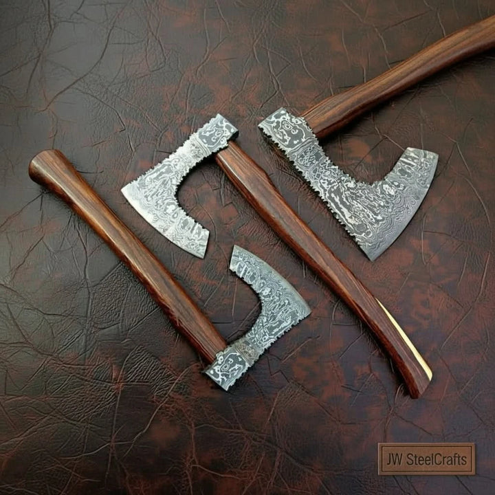     Collection of handmade Damascus steel axes with wooden handles displayed on textured leather background.