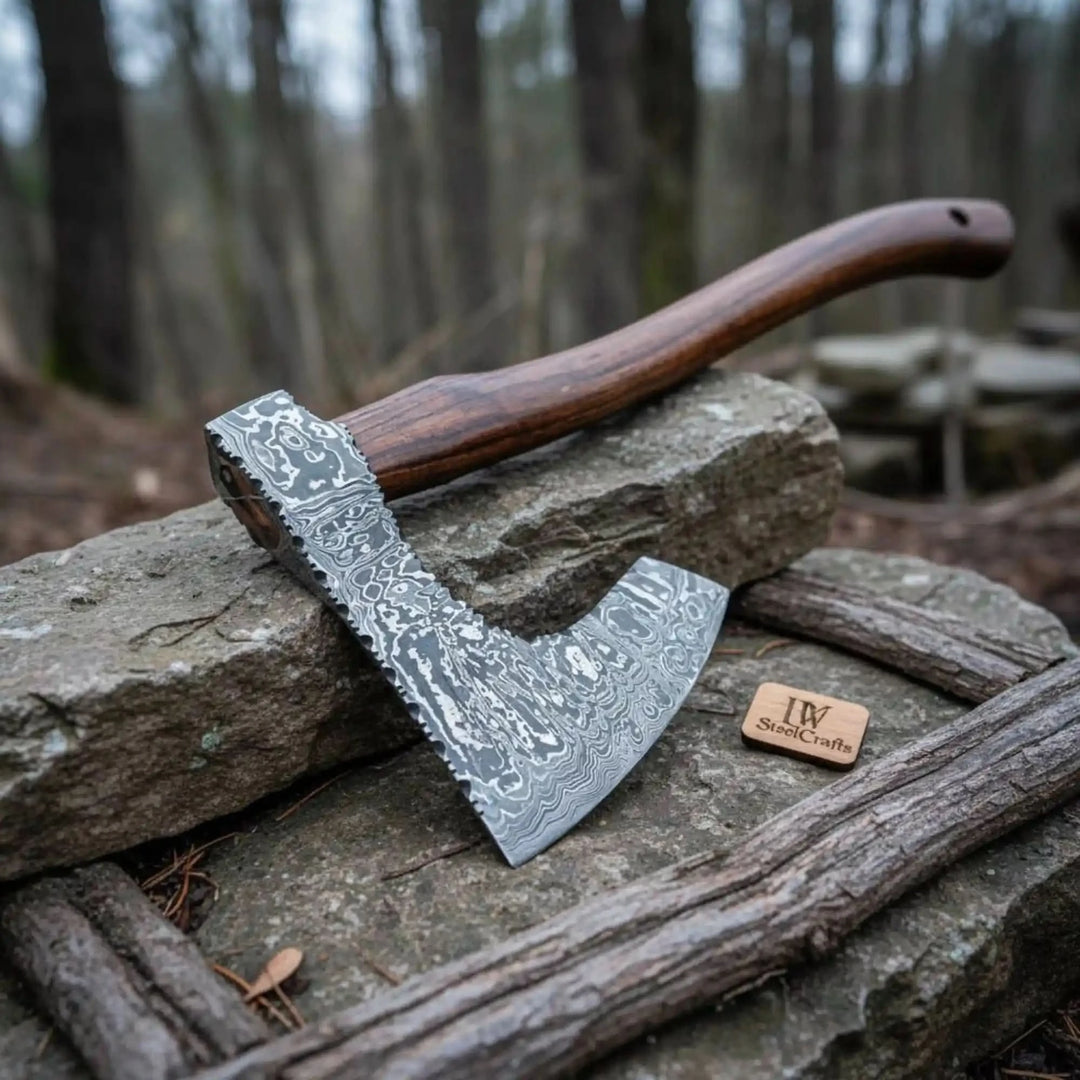     Forged steel camping axes with engraved patterns and handcrafted wooden shafts displayed indoors.