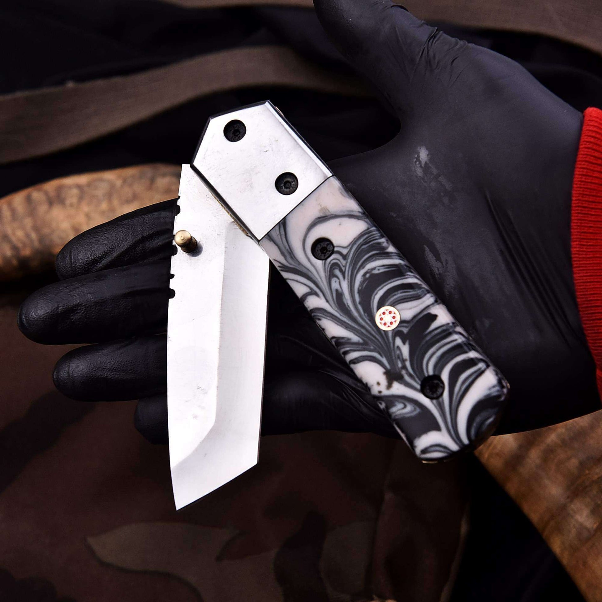 Handmade stainless steel folding knife with marble resin handle and liner lock, shown open in hand