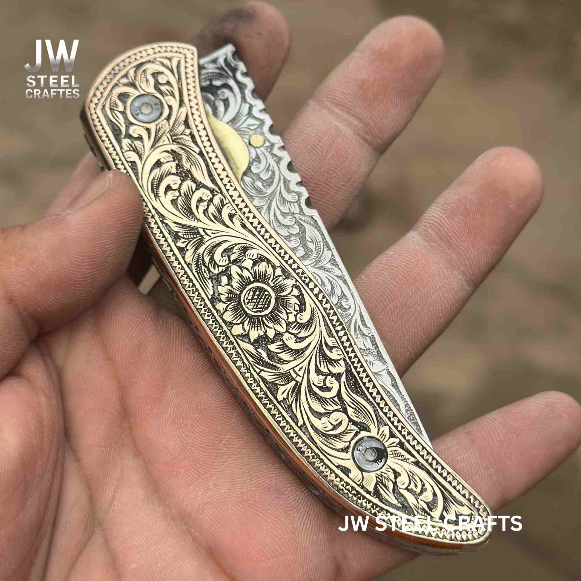 Decorative knife with intricate patterns held in a hand, branded 'JW Steel Craftes'.