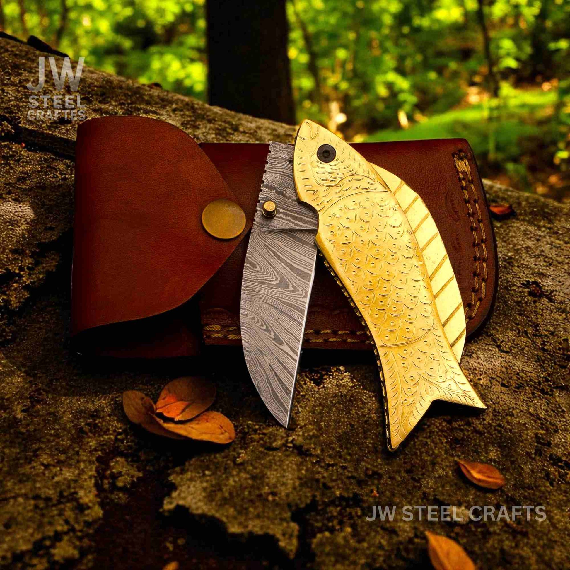Two fish-shaped knives, one gold and one silver, on a wooden surface with a natural background.