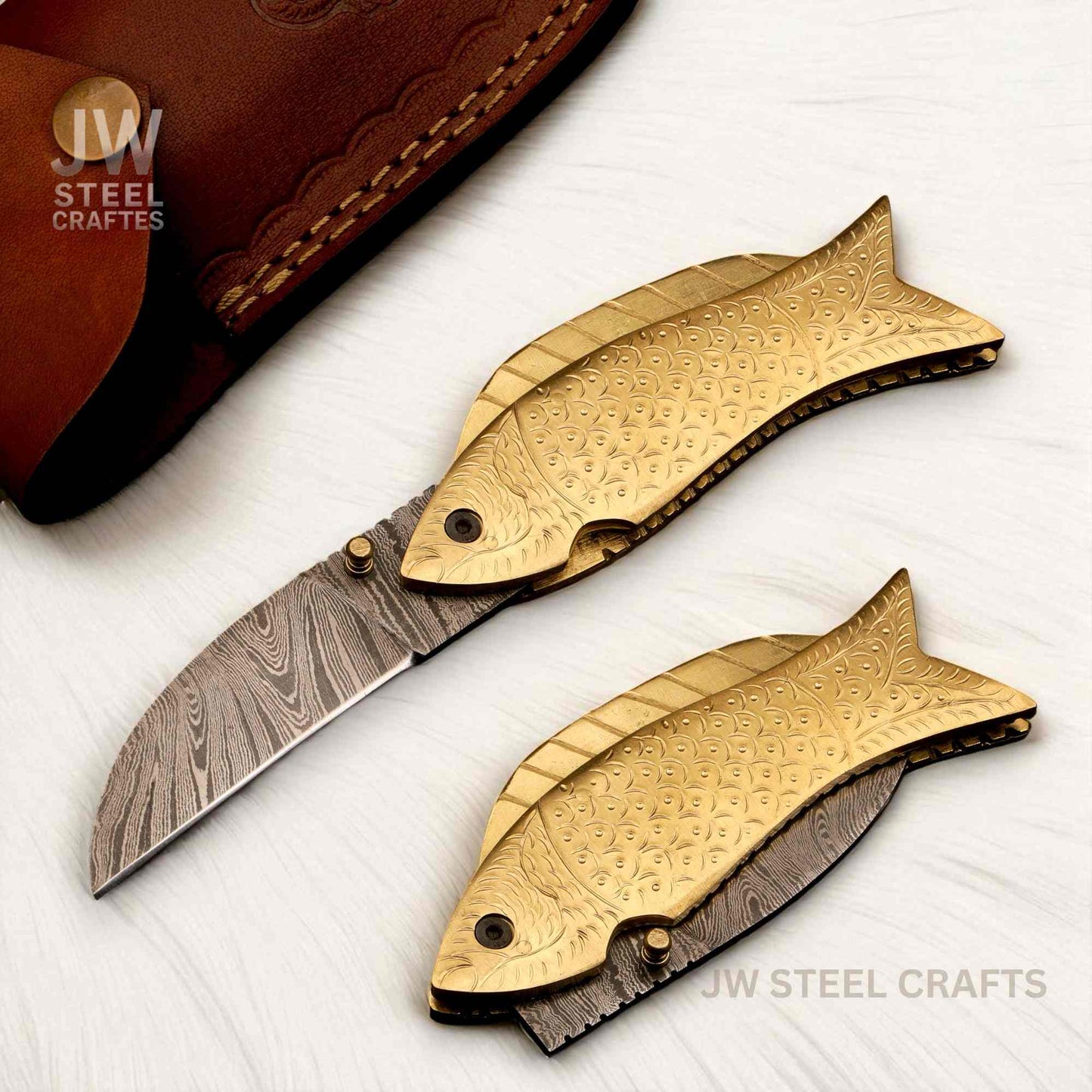 Fishing-themed knife with gold fish design on a white surface, branded 'JW Steel Crafts'.