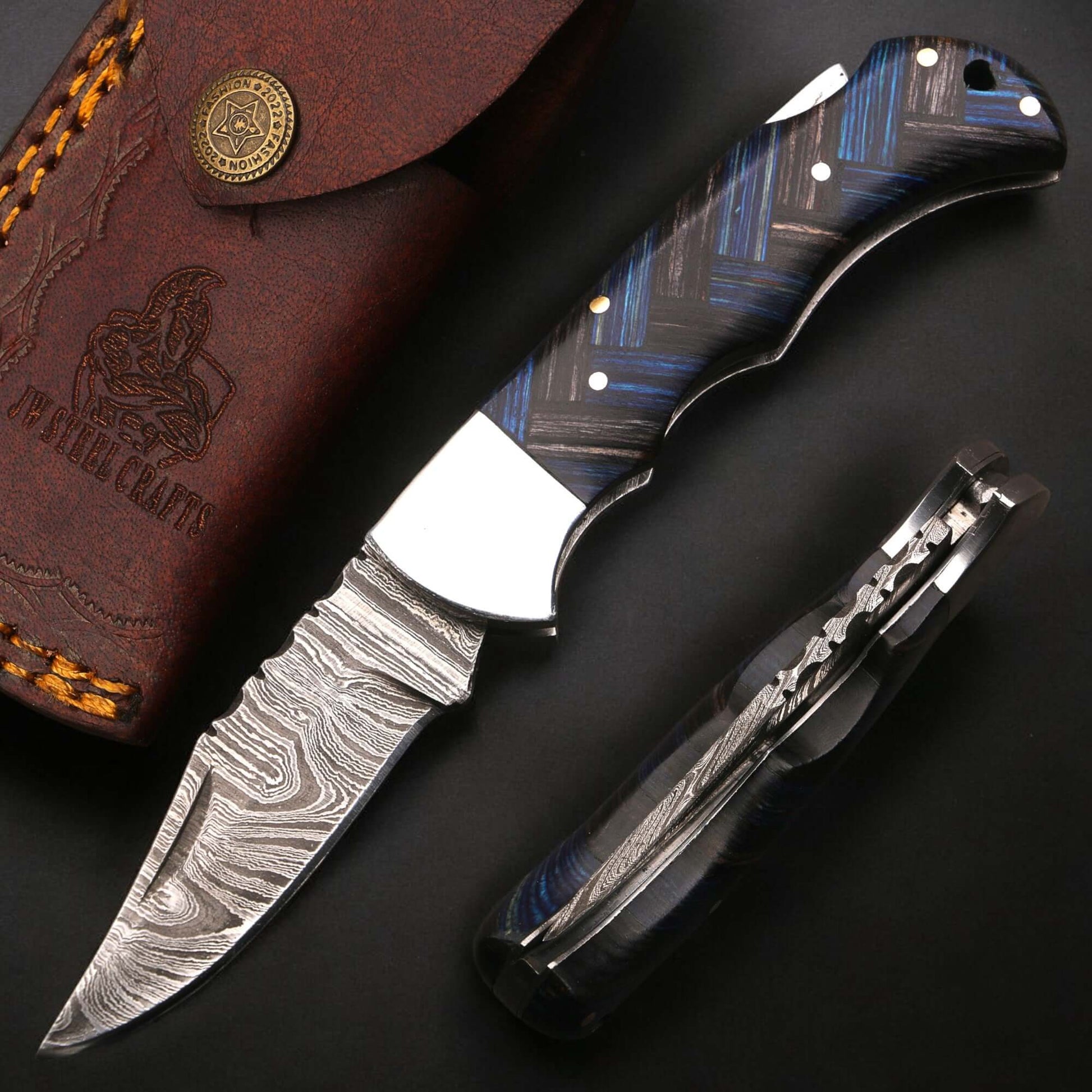 Damascus steel folding knife with pakka wood handle and stainless steel bolster, shown open and folded side by side on a dark background to highlight blade pattern, handle contours, and folding mechanism.