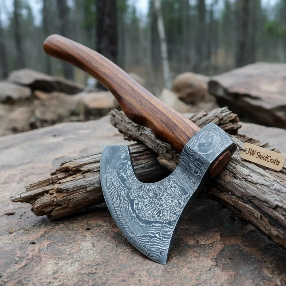     Gravelthorn custom steel hatchet resting on aged timber with decorative Damascus blade engravings and wooden grip.