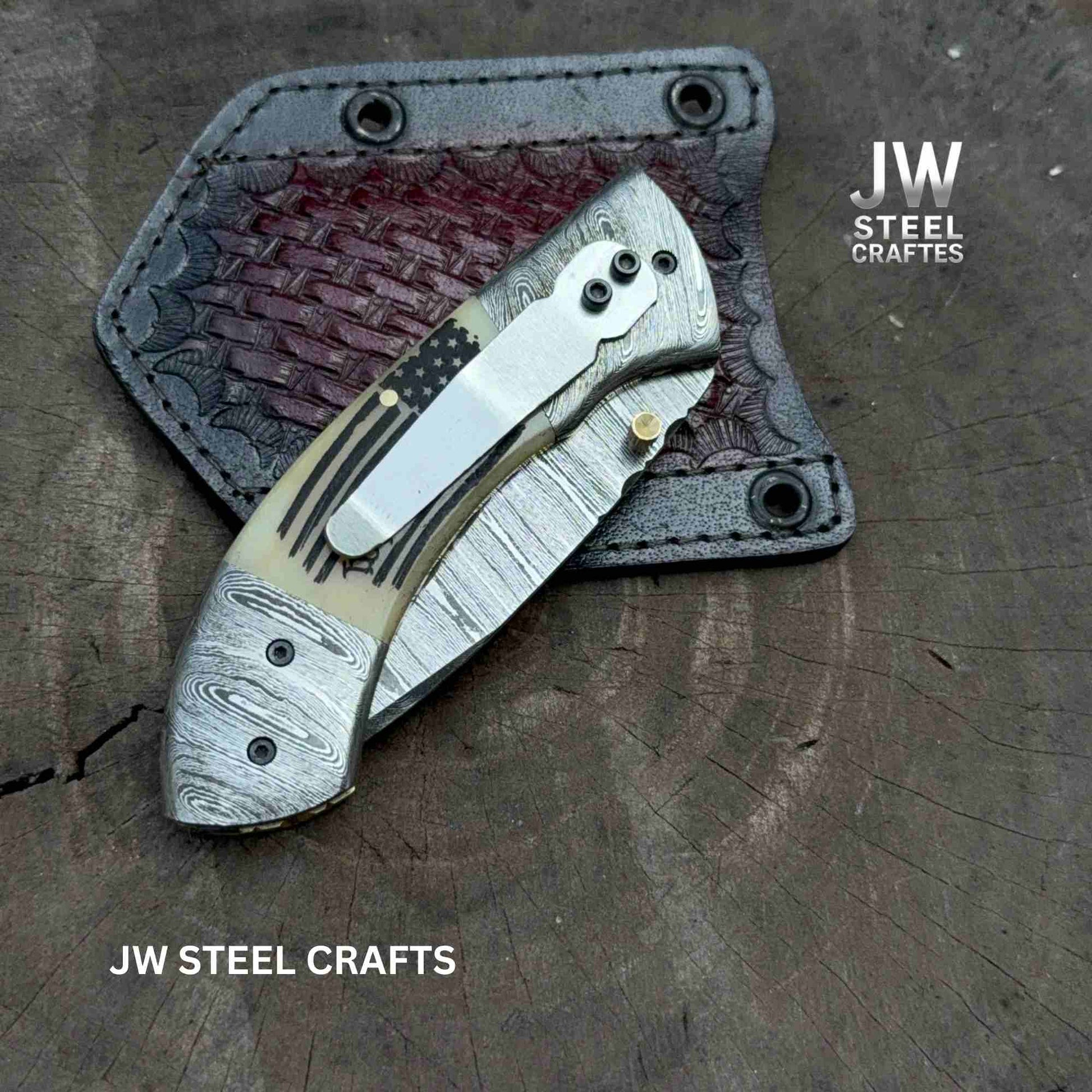 Folding knife with leather sheath on a wooden surface, branded 'JW Steel Crafts'.
