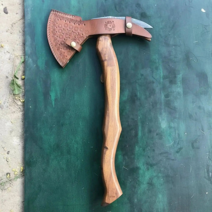     Kingshade Damascus expedition axe posed dramatically in a tree stump with glowing fire and rugged wilderness backdrop.
