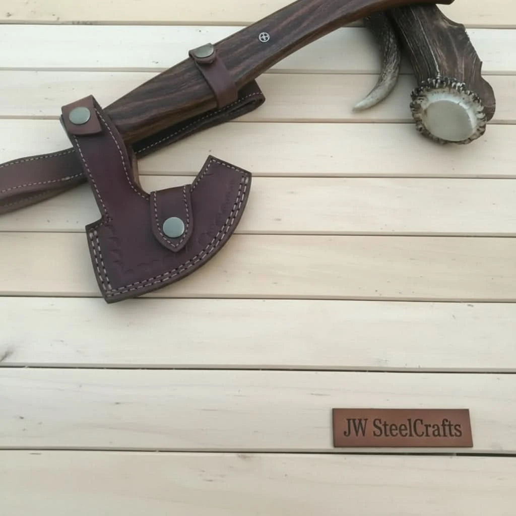    Quartzpine custom outdoor hatchet with decorative Damascus steel blade and stitched leather carrying case outdoors.
