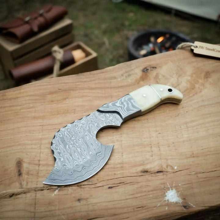     Mistyforge premium handmade Damascus knife with engraved blade textures and smooth ivory scales photographed outdoors.