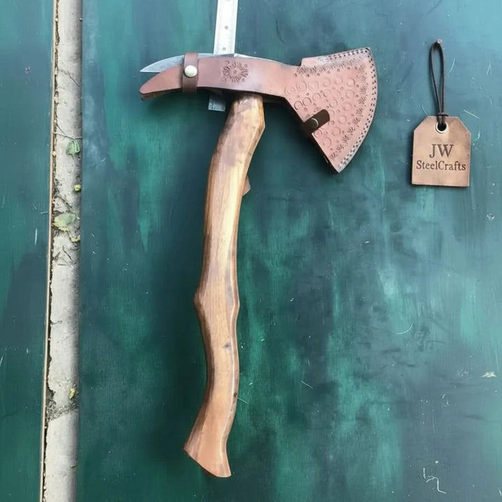     Oakshadow premium Damascus hatchet resting on weathered wood with decorative forged patterns and warm forest fire ambiance.