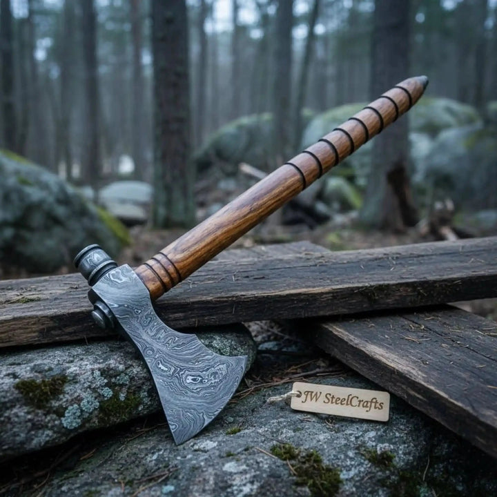     Oakshadow handmade bushcraft Damascus axe resting on tan leather with engraved blade craftsmanship.