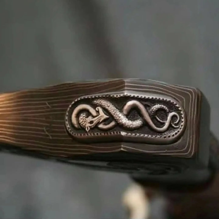     Bushcraft axe and knife featuring engraved blades and carved wooden handles in woodland setting.