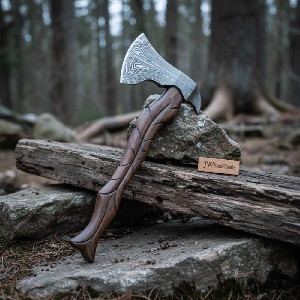     Handcrafted Damascus forest axe with spiral carved handle resting beside weathered wood logs.