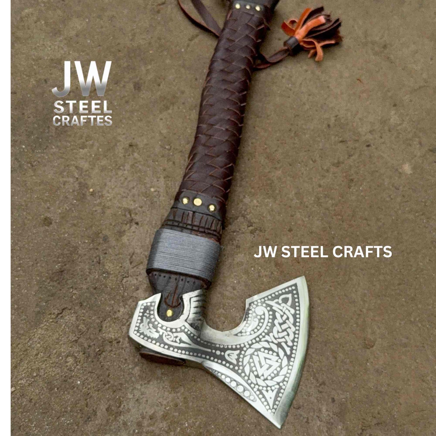 Decorative axe with braided leather handle on a textured surface, branded 'JW Steel Crafts'.