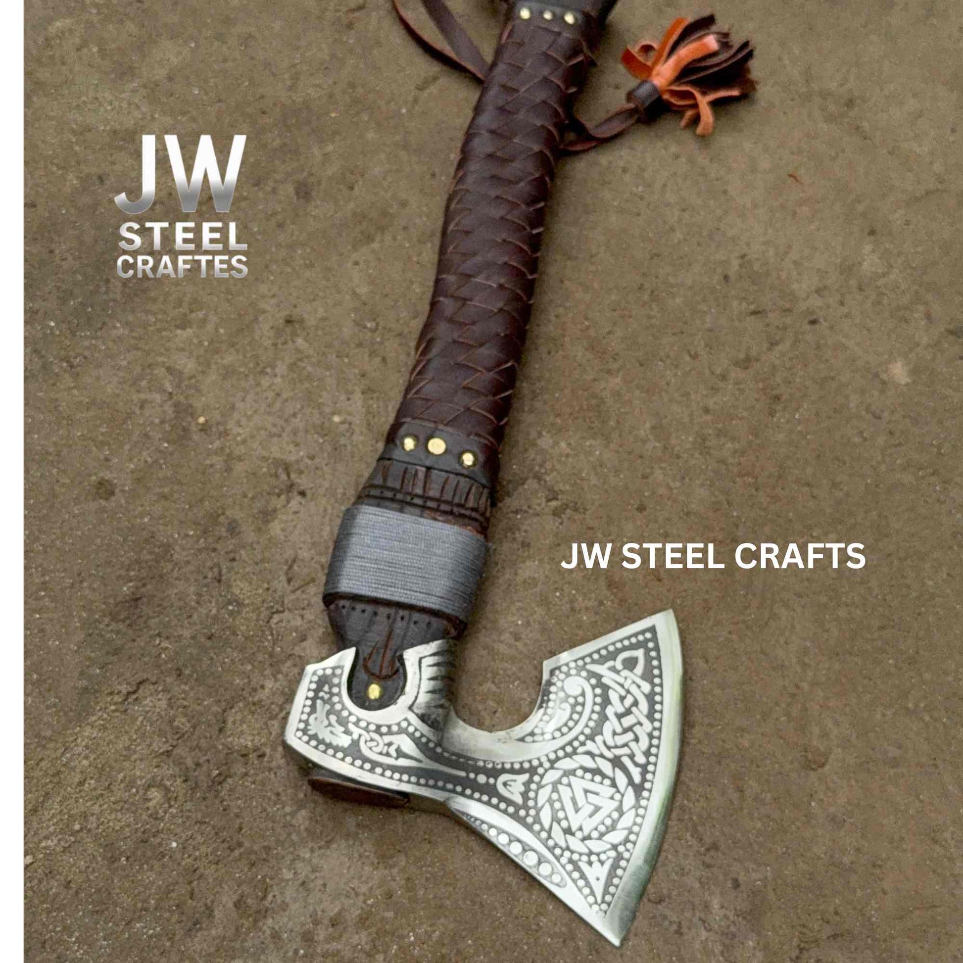 Decorative axe with braided leather handle on a textured surface, branded 'JW Steel Crafts'.