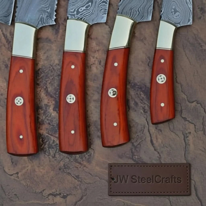 Rustic chef cutlery composition featuring rich red wood handles with silver rivets against textured stone surface.