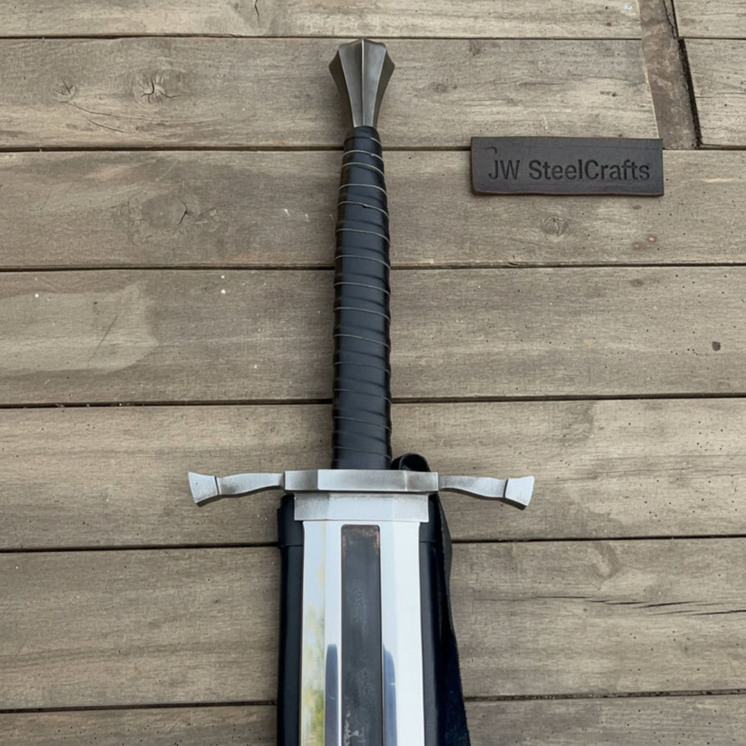 Dragon Slayer greatsword with a massive slab blade, black cord grip, and carry case displayed on a rustic wood plank
