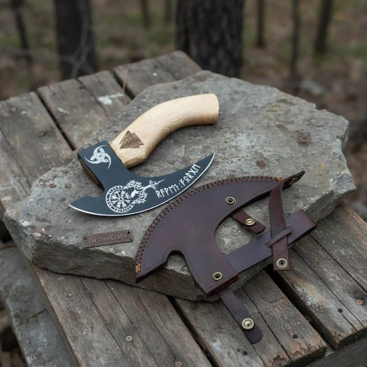 Detailed view of a black blade Viking hatchet with decorative engravings and ergonomic ash wood handle.
