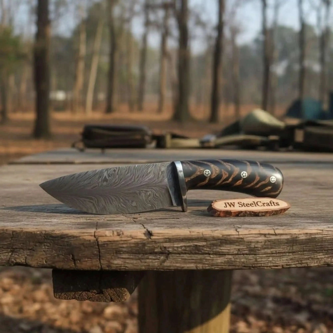 fixed blade knife set with black handles, silver guards, patterned blades, and forest product photography.