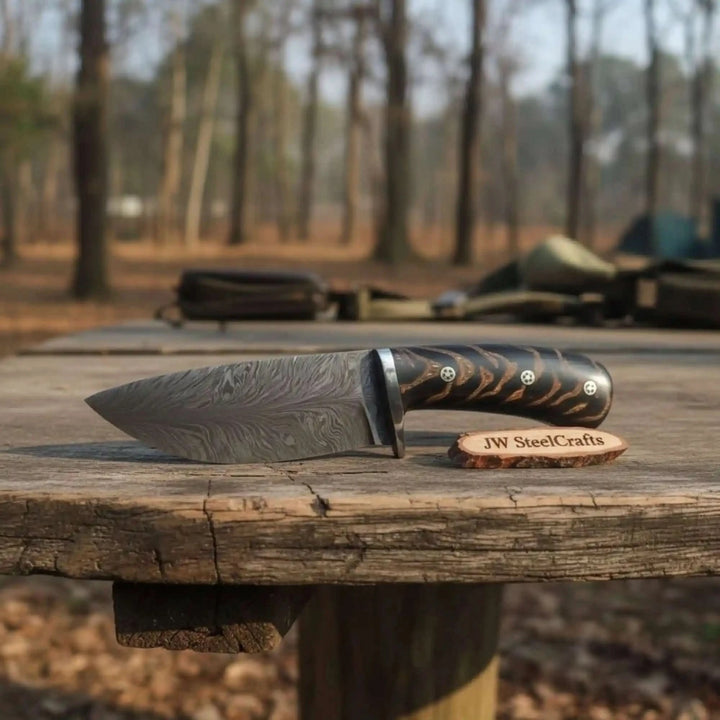 fixed blade knife set with black handles, silver guards, patterned blades, and forest product photography.