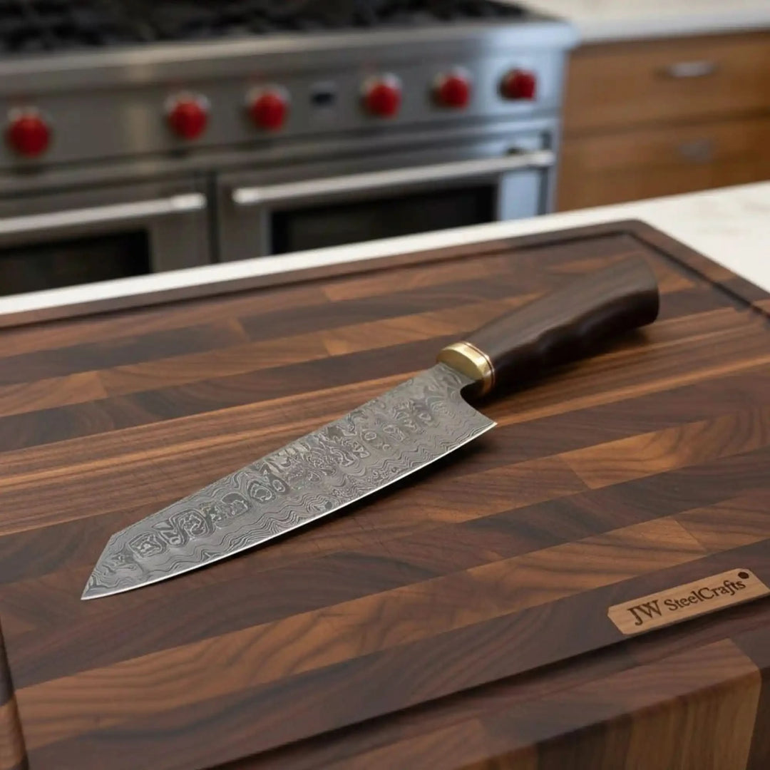 Narrow chef blade with Damascus pattern resting diagonally across a butcher block board