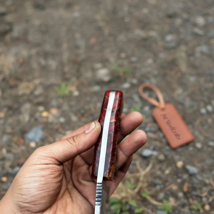 Sharp field knife with natural wood handle, polished blade, and JW SteelCrafts tag on a round tree stump.