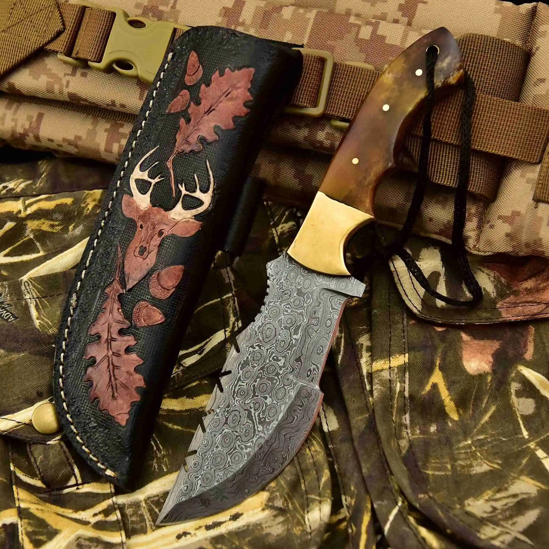 Camouflage background handmade skinner knife set showing a tooled black leather sheath and brown handle Damascus knife