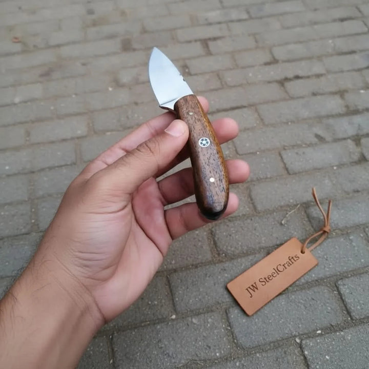 Outdoor camping knife with wood handle, smooth steel blade, decorative pin, and JW SteelCrafts tag beside it.