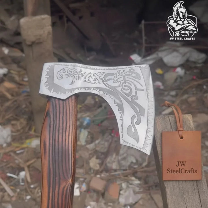 Closeup of hand forged carbon steel Viking axe head with traditional engraved detailing and leather grip wrap