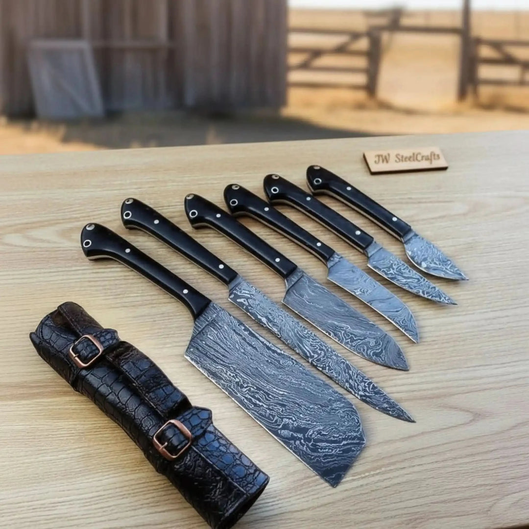 Kitchen chef knives with Damascus patterned steel and polished ergonomic black handles.