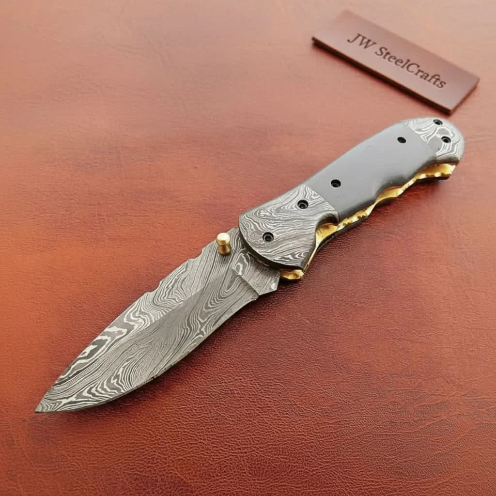     Sharp Damascus pocket knife designed with curved handle shape and layered steel blade texture