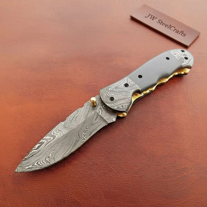     Sharp Damascus pocket knife designed with curved handle shape and layered steel blade texture