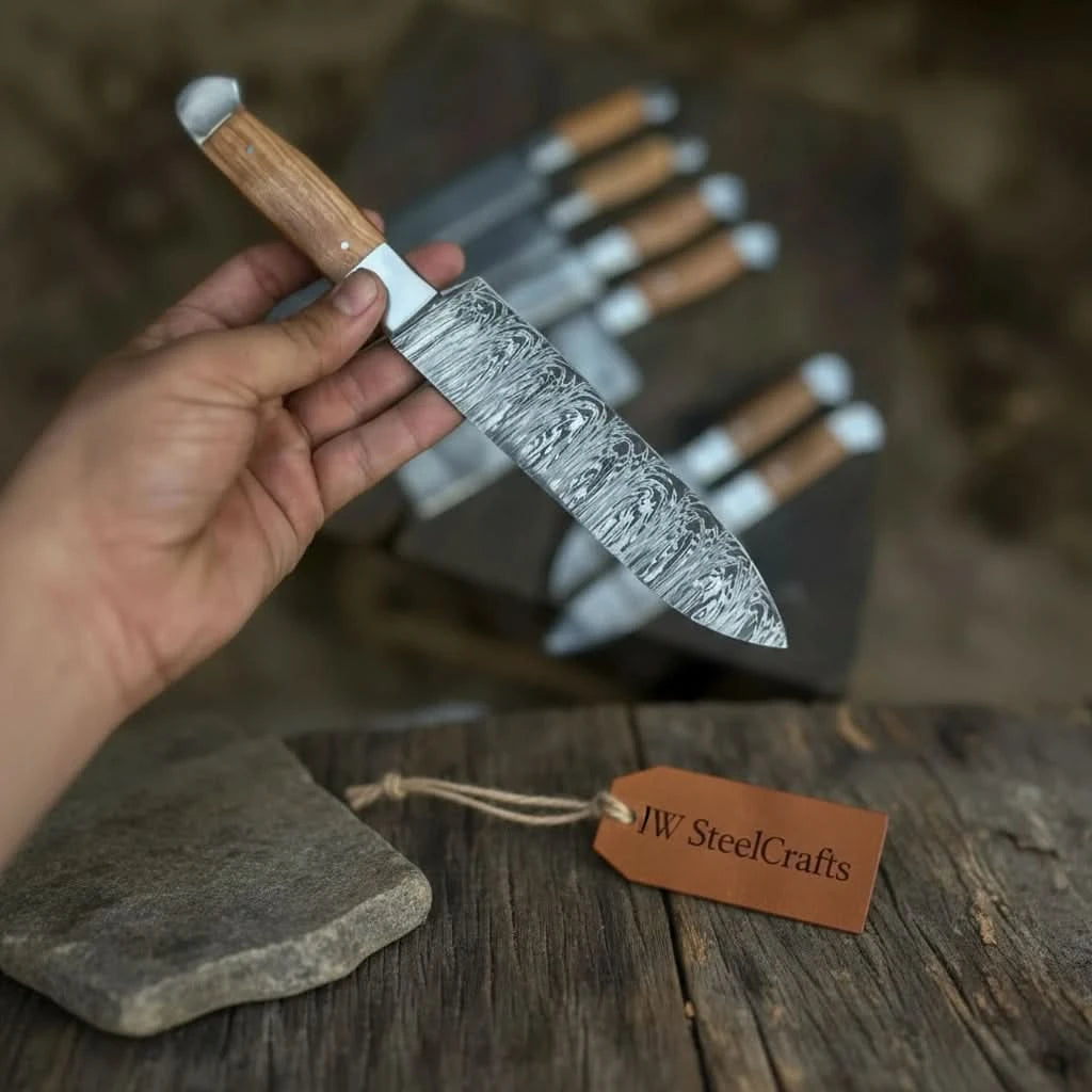Detail shot of a custom hand-forged Damascus blade with swirling steel pattern and warm-toned wooden grip, part of a matching kitchen knife collection
