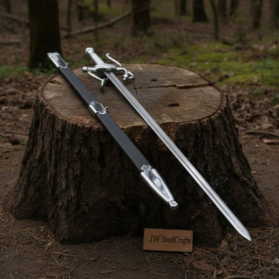 Full sword and scabbard set by JW SteelCrafts resting on a tree stump in a dark woodland, highlighting the contrast of the silver blade and black sheath.